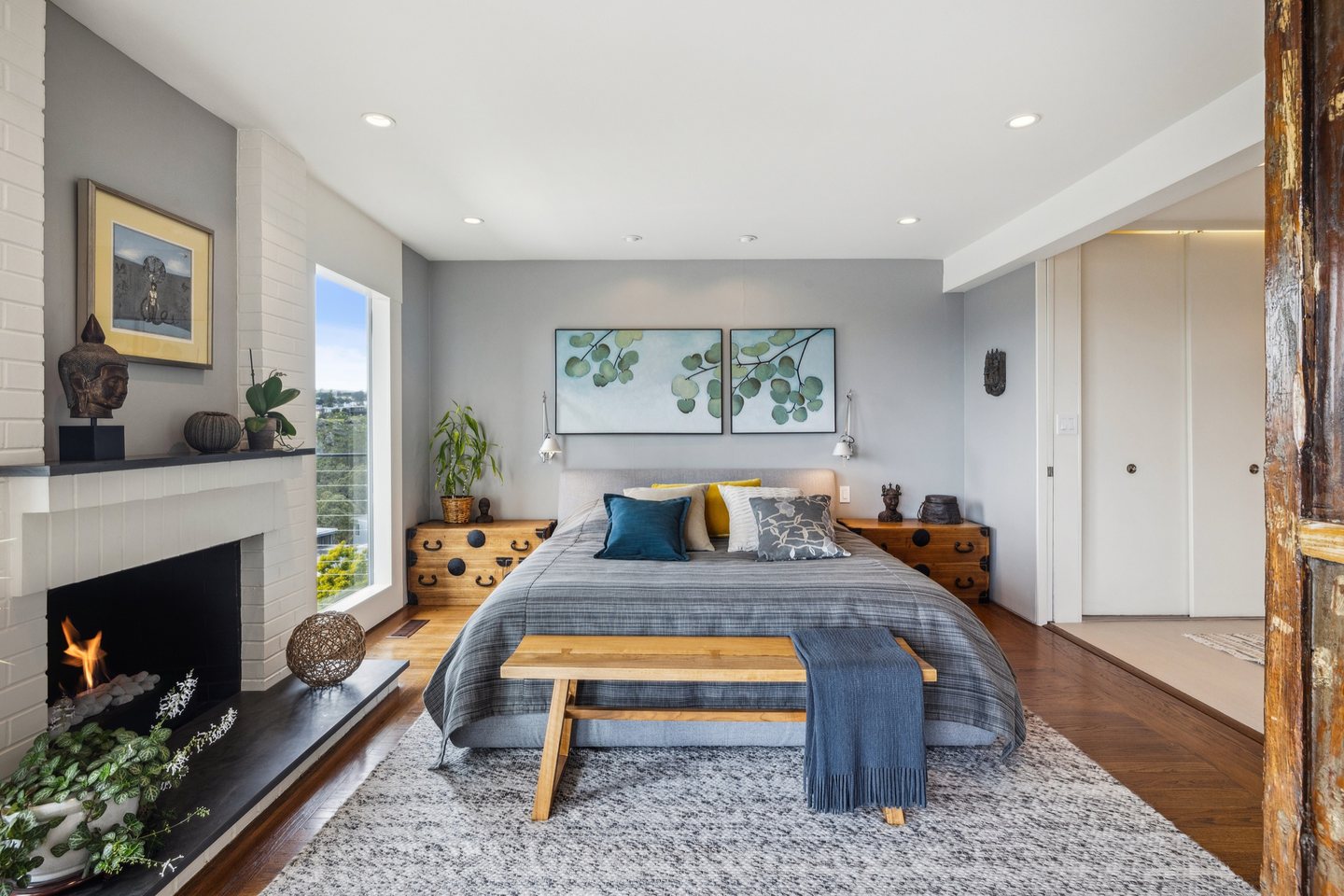 Bedroom with a dark stone fireplace surround beneath a wall-mounted television