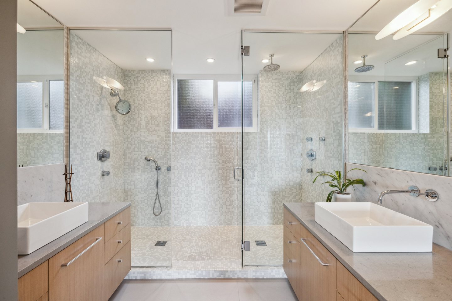 Primary bathroom with stone vanity surfaces, a built-in tub, and warm wood cabinetry