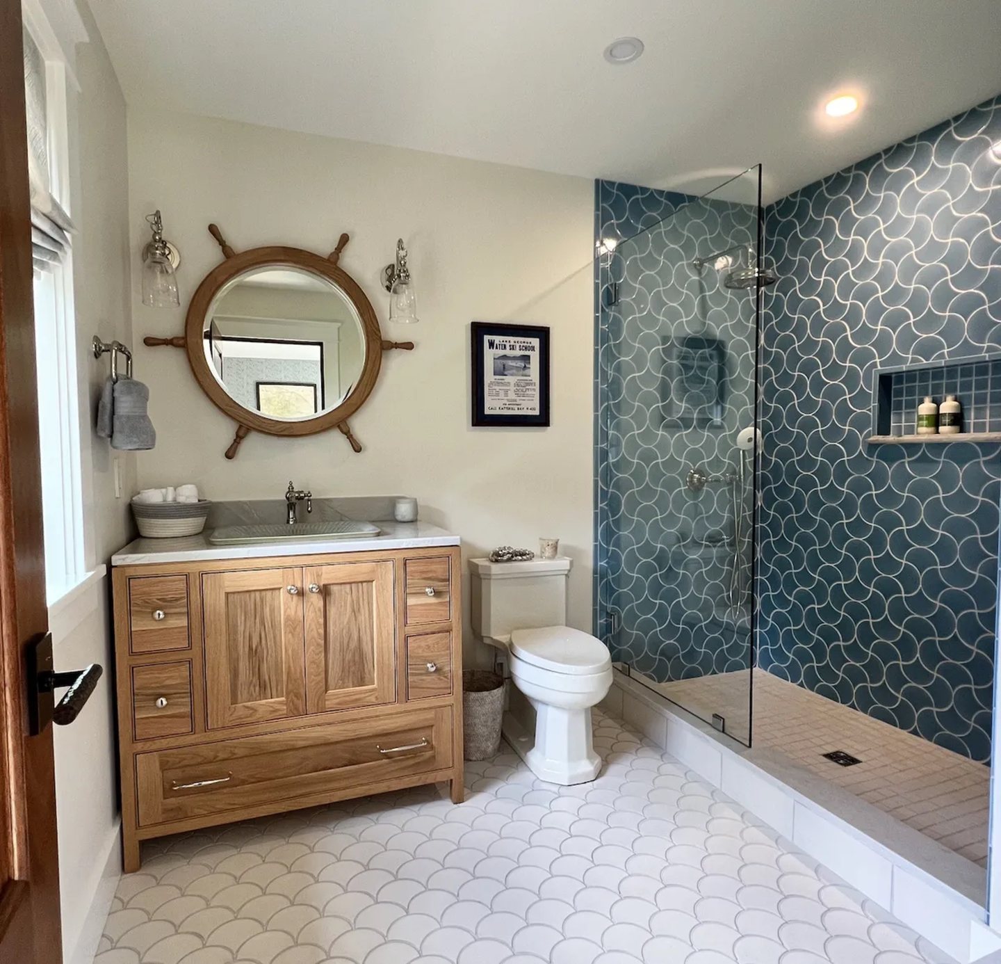 Blue scallop tile shower and white mosaic tile floor in a coastal-style bathroom