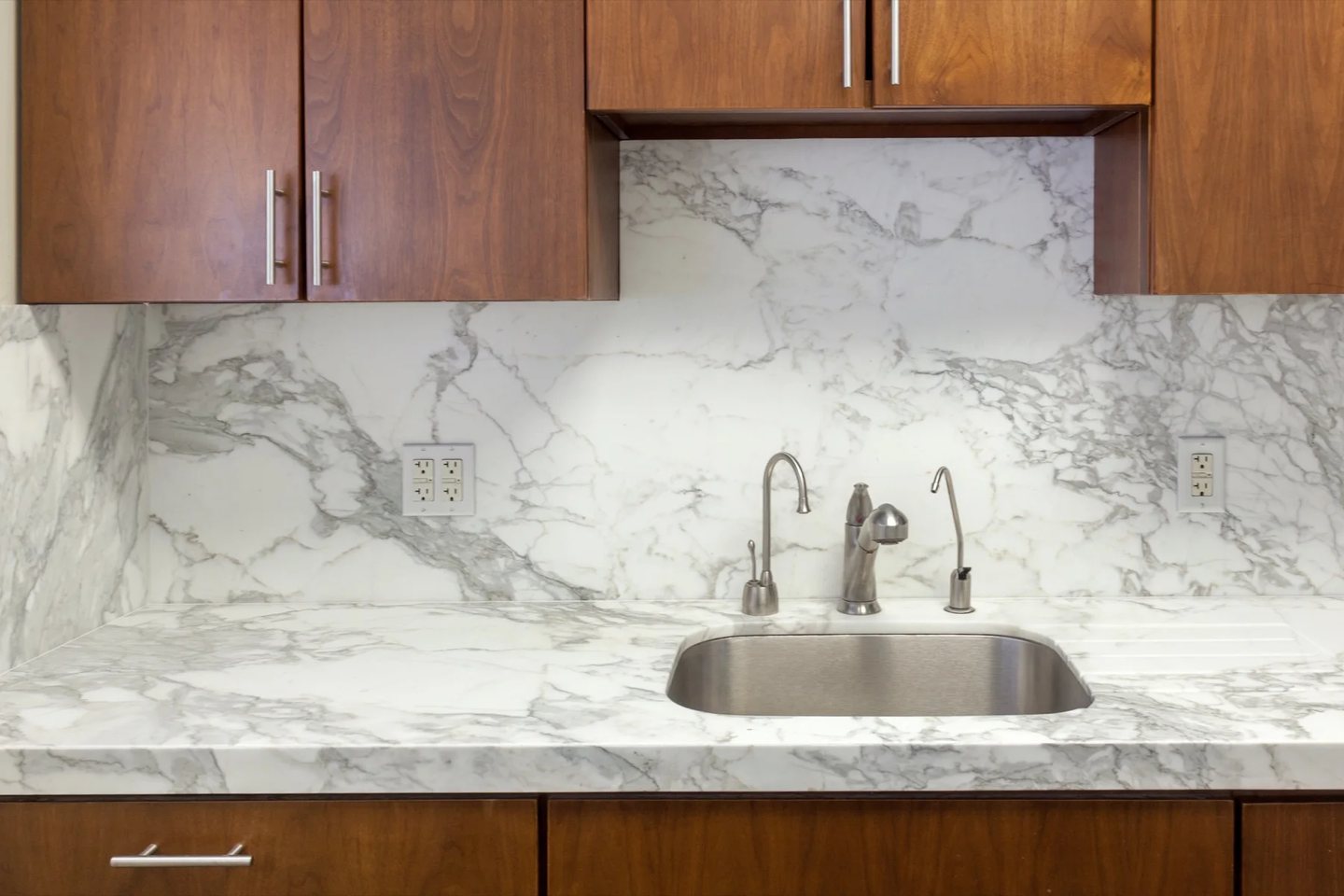 Marble counter, sink, backsplash, and full-height stone